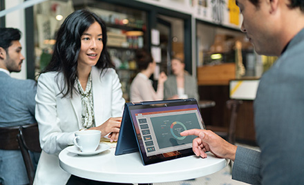 Image of two workers meeting over a table and an HP Elite Dragonfly
