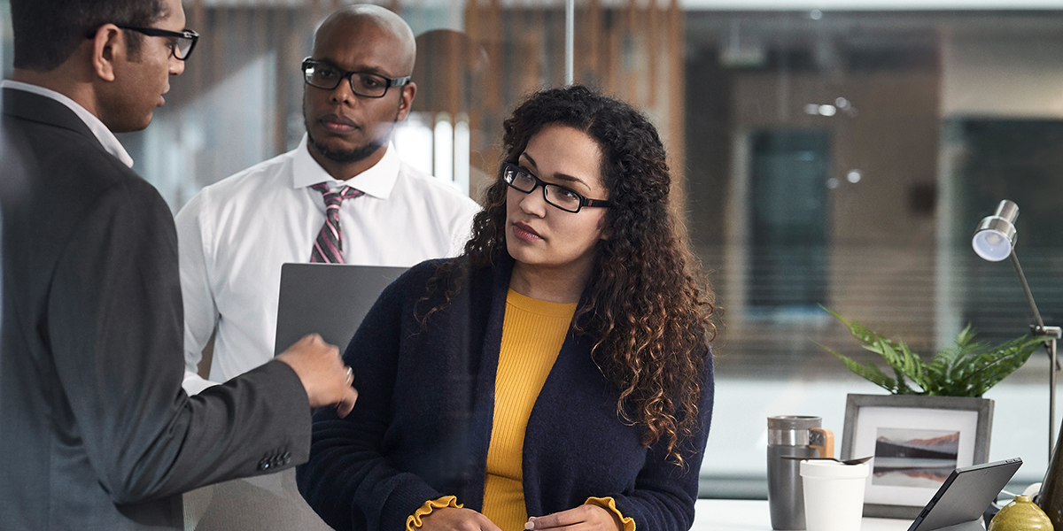 Image of three workers collaborating beside a desktop