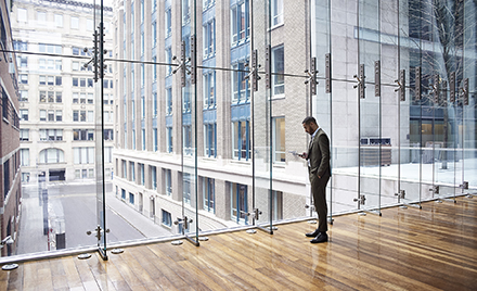 Image of a worker checking his phone while looking out a window over a cityscape