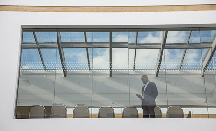Image of a worker standing by a window looking at his phone