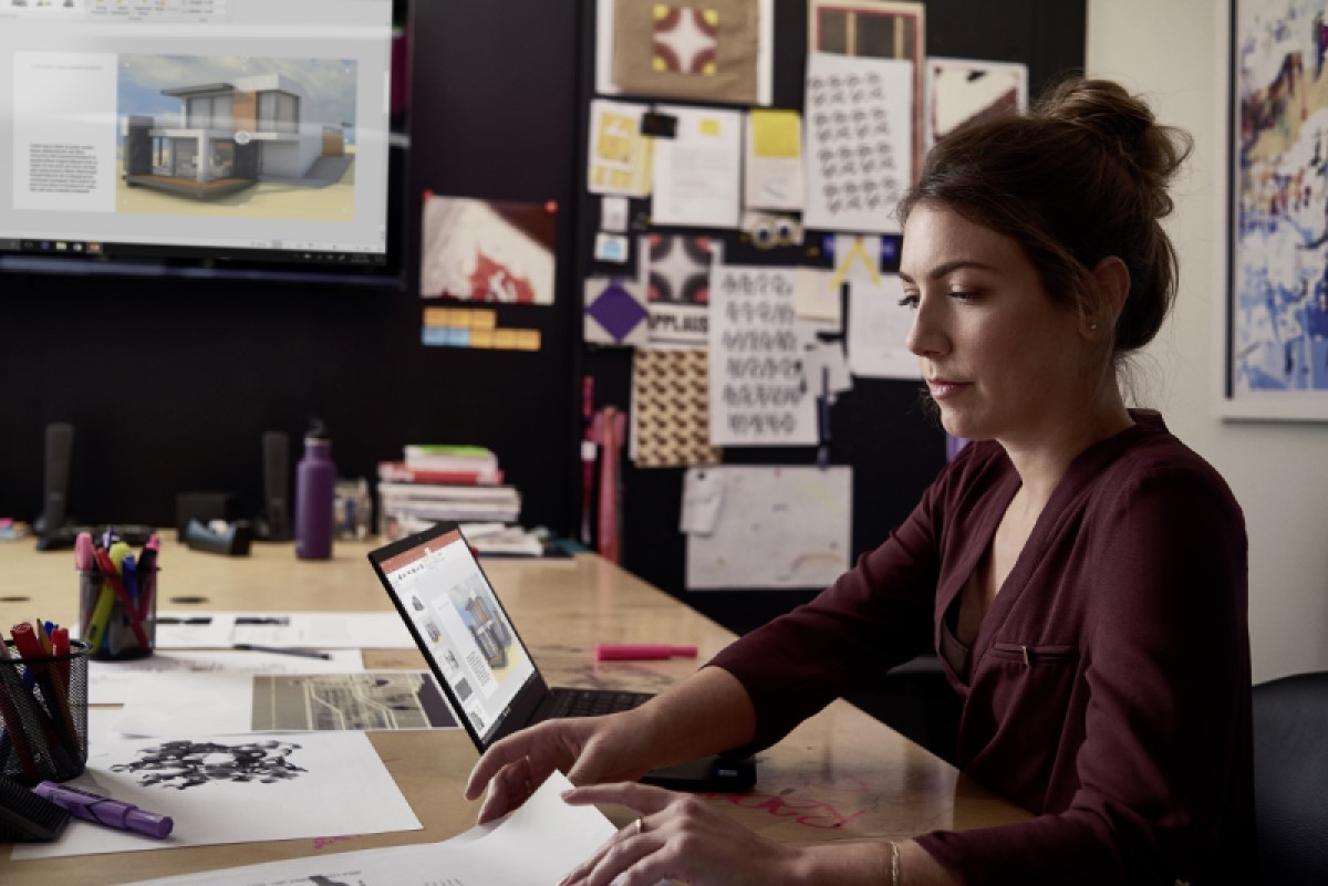 Female small business professional working on designs using devices running PowerPoint