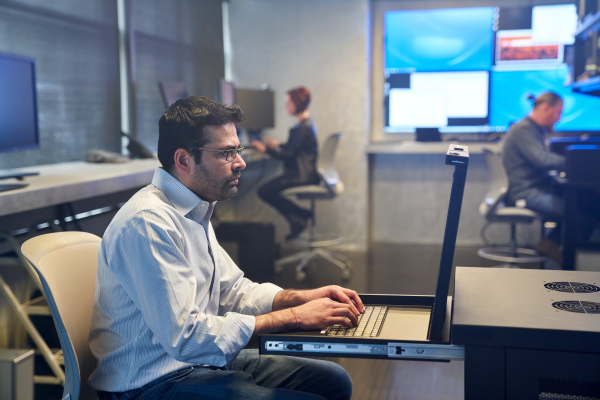 Man in a collared shirt working on a server station inside a secure room