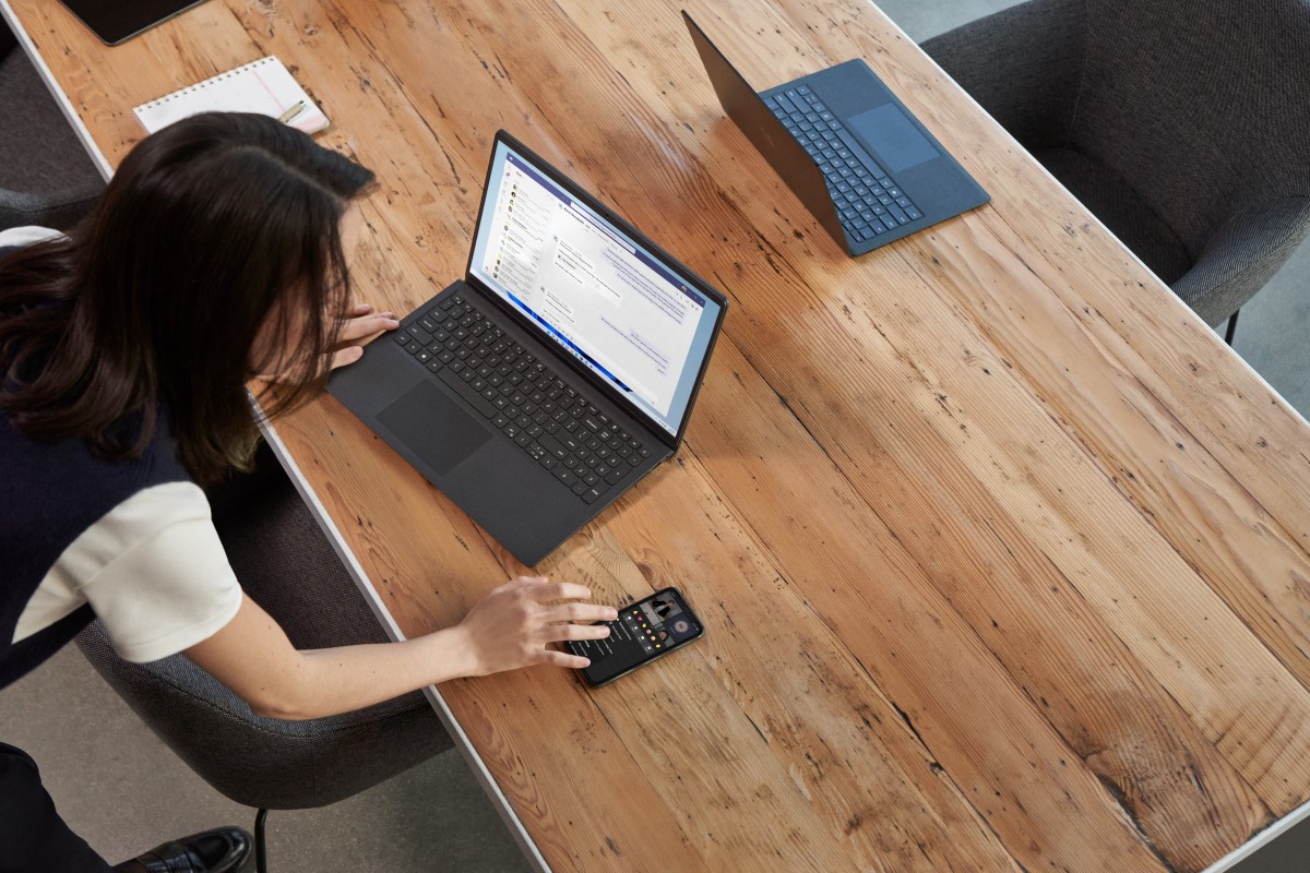 A woman reacting to a Teams meeting from her mobile phone while participating in a Microsoft Teams meeting