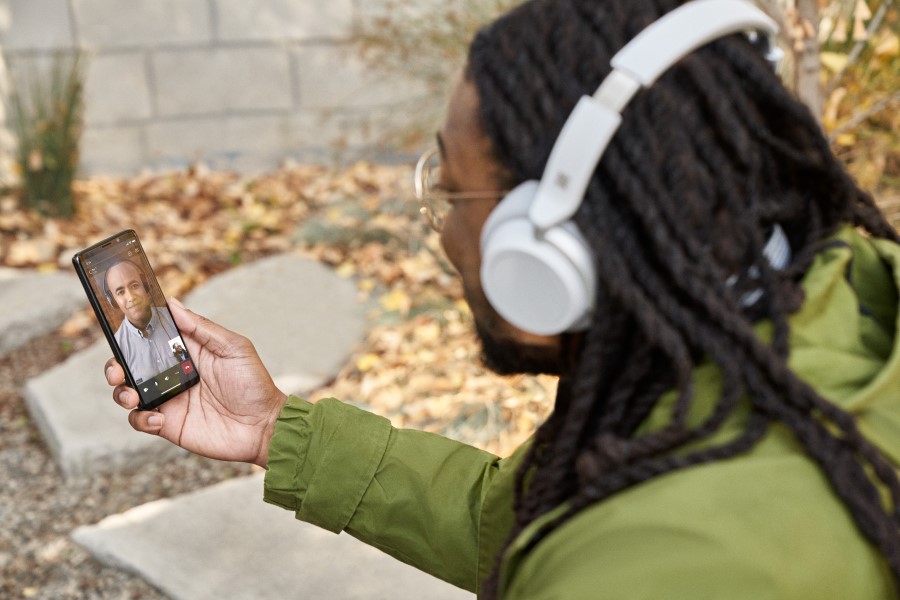 A man participating in a Microsoft Teams video call on his mobile phone while sitting outside​