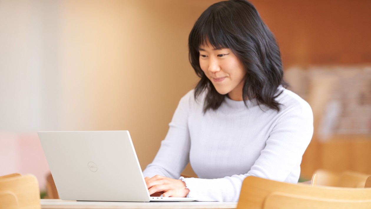 Woman smiling and engaged at laptop on desk