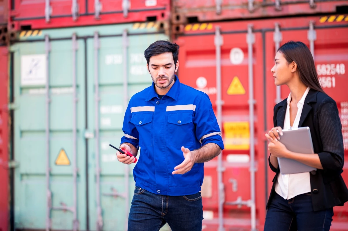 Two people standing in front of shipping containers