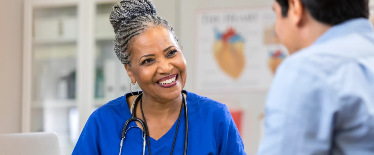 A person in scrubs smiling looking at another person