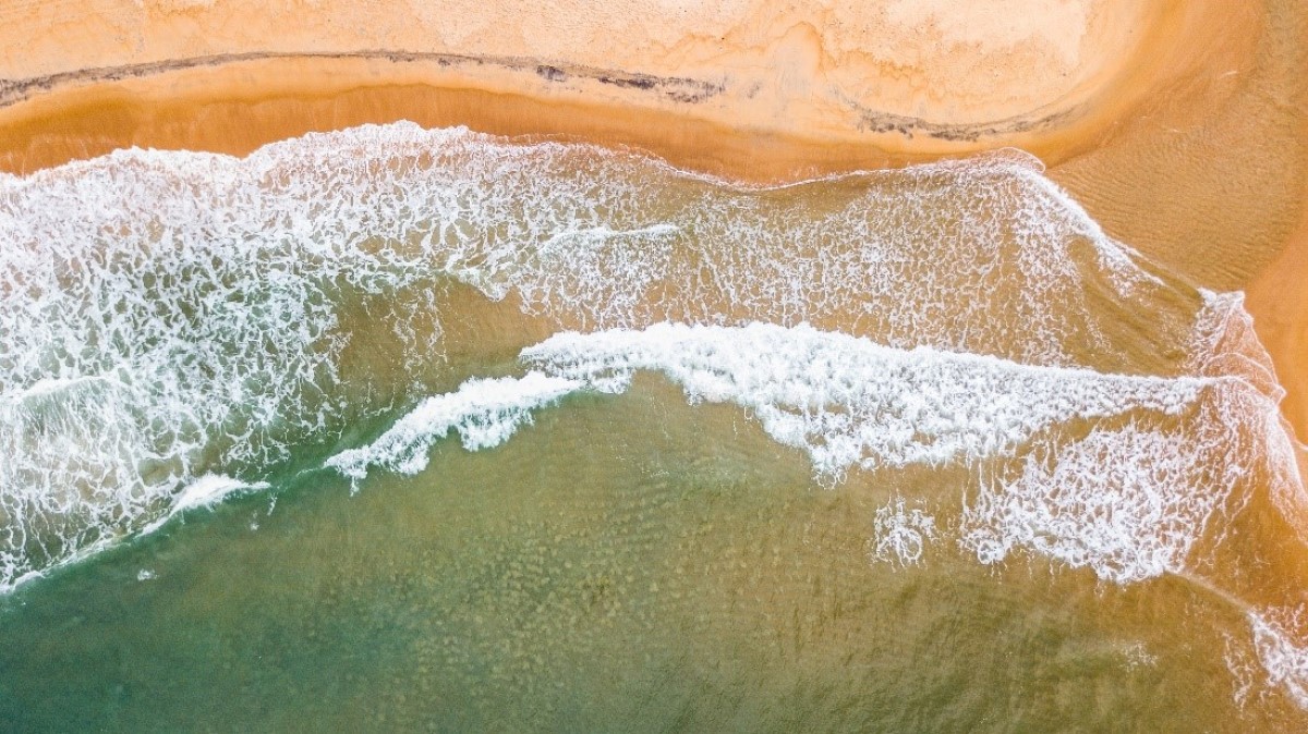 Waves of ocean surf washing onto a beach