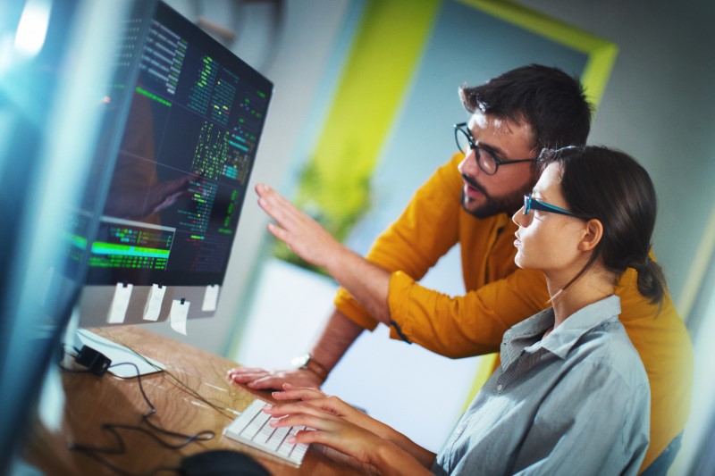 a man and a woman working together in front of a computer