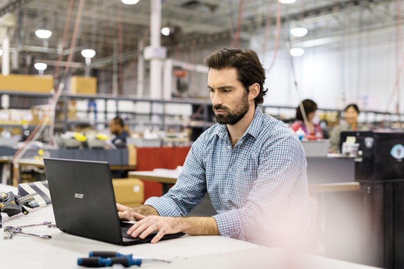 Male first line worker sitting at workstation in commercial manufacturing plant