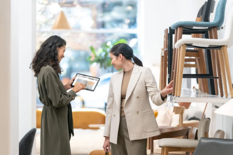 A retail store associate helping a customer by searching for inventory on her shared device