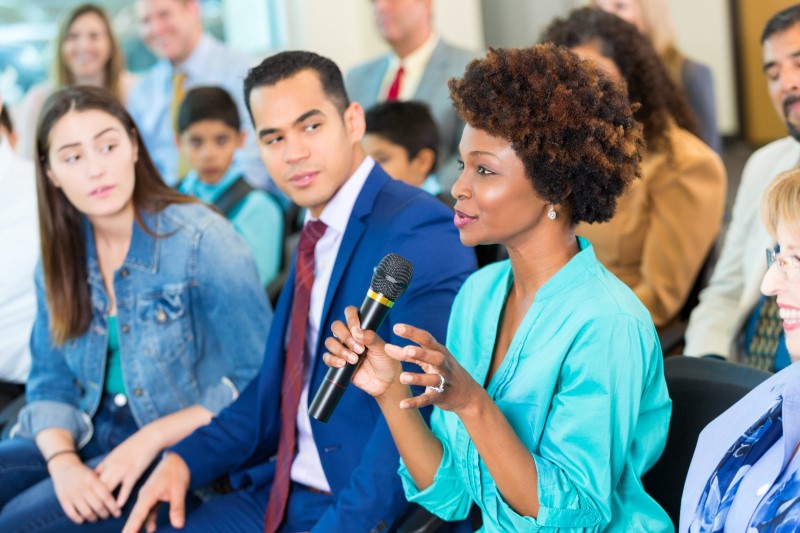 A woman gestures while asking a political candidate a question during a town hall meeting