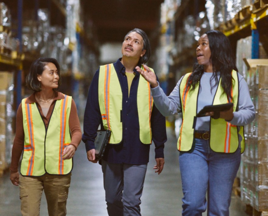 Warehouse workers walking through the aisle; manager reviewing and sharing data real time to make intelligent decisions powered by Azure