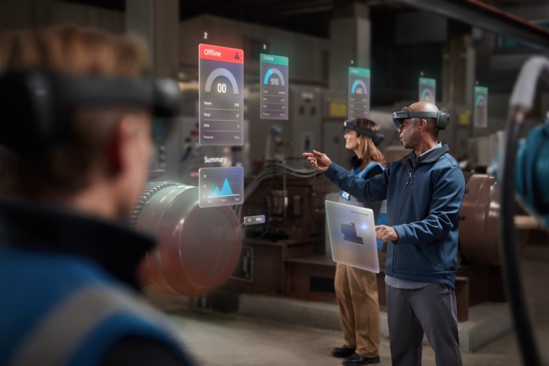 Two men and a woman collaborating using Microsoft Hololens 2 on the manufacturing floor. Contains hologram scenario. Contextual imagery
