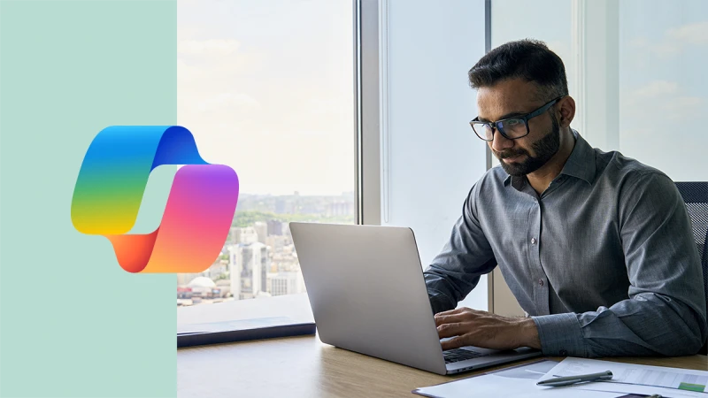 [3:38 PM] Jenn Sarfaty (Wipro Designit Services Inc) Executive sitting at desk using laptop in an office with a panoramic view. Including Copilot logo