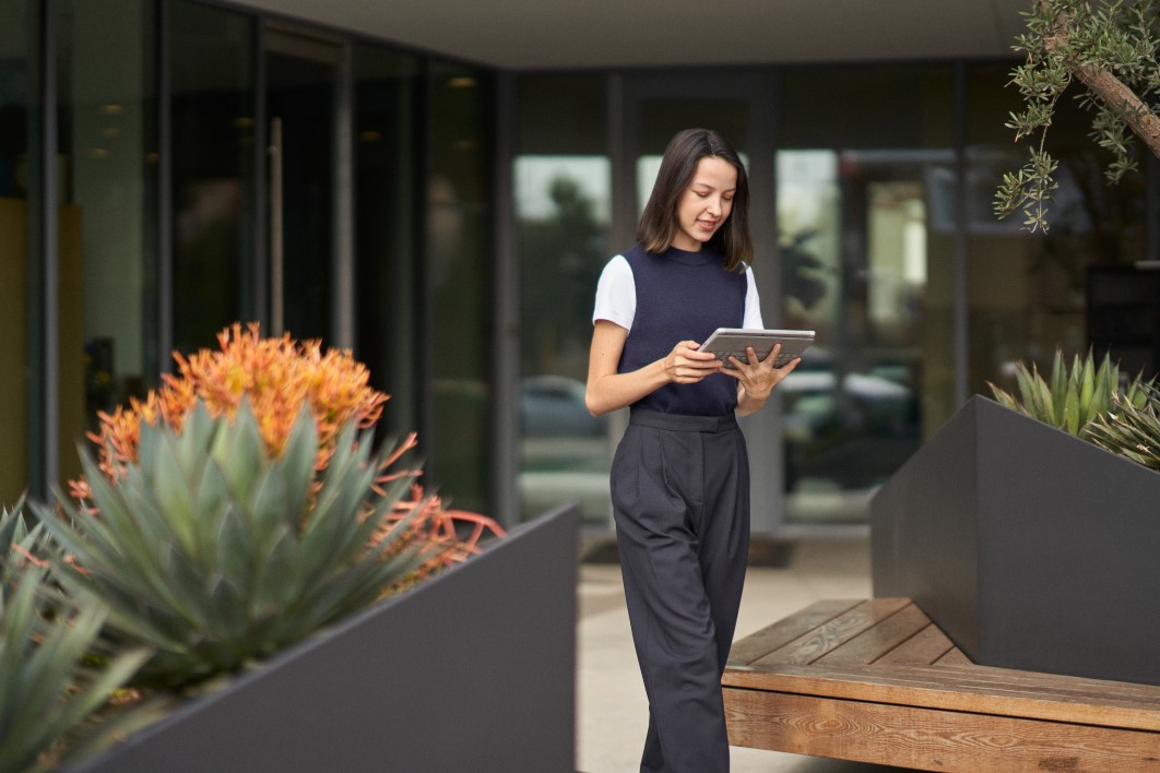 A woman participating in a Microsoft Teams meeting on her Surface tablet while on the go