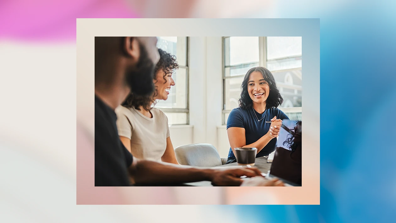 A diverse group of coworkers collaborate in an office space while one takes notes on his laptop