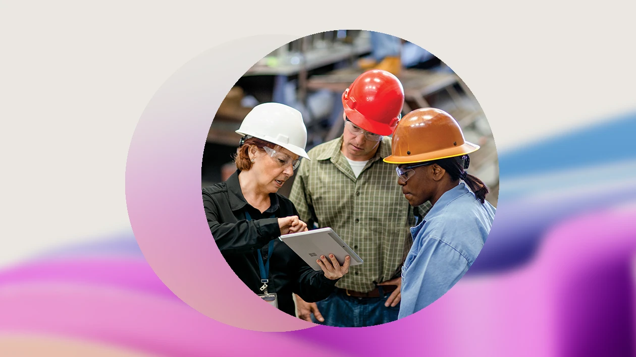 Three warehouse workers discuss over a tablet
