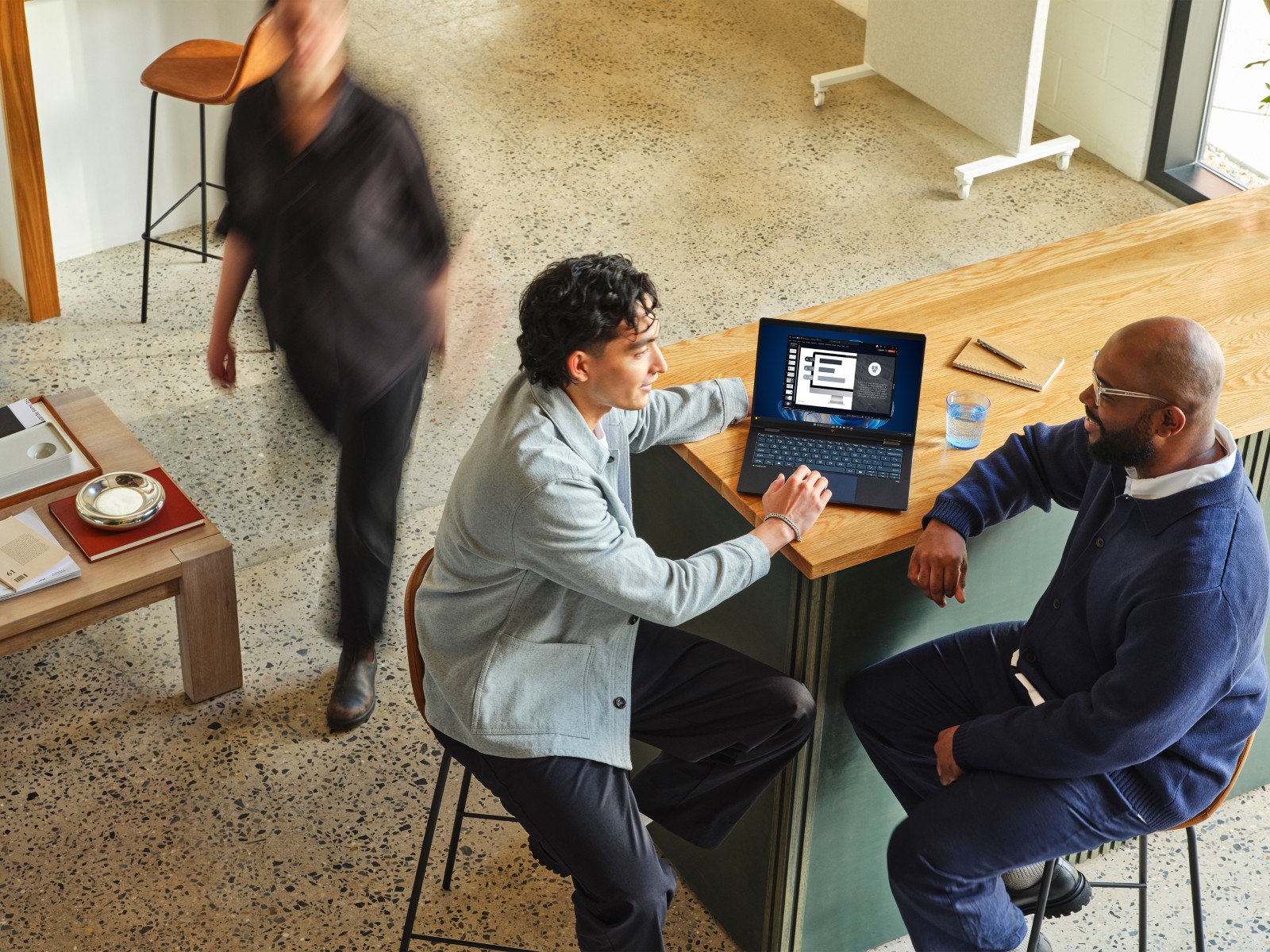 Two people in conversation while reviewing information on a laptop in a professional setting