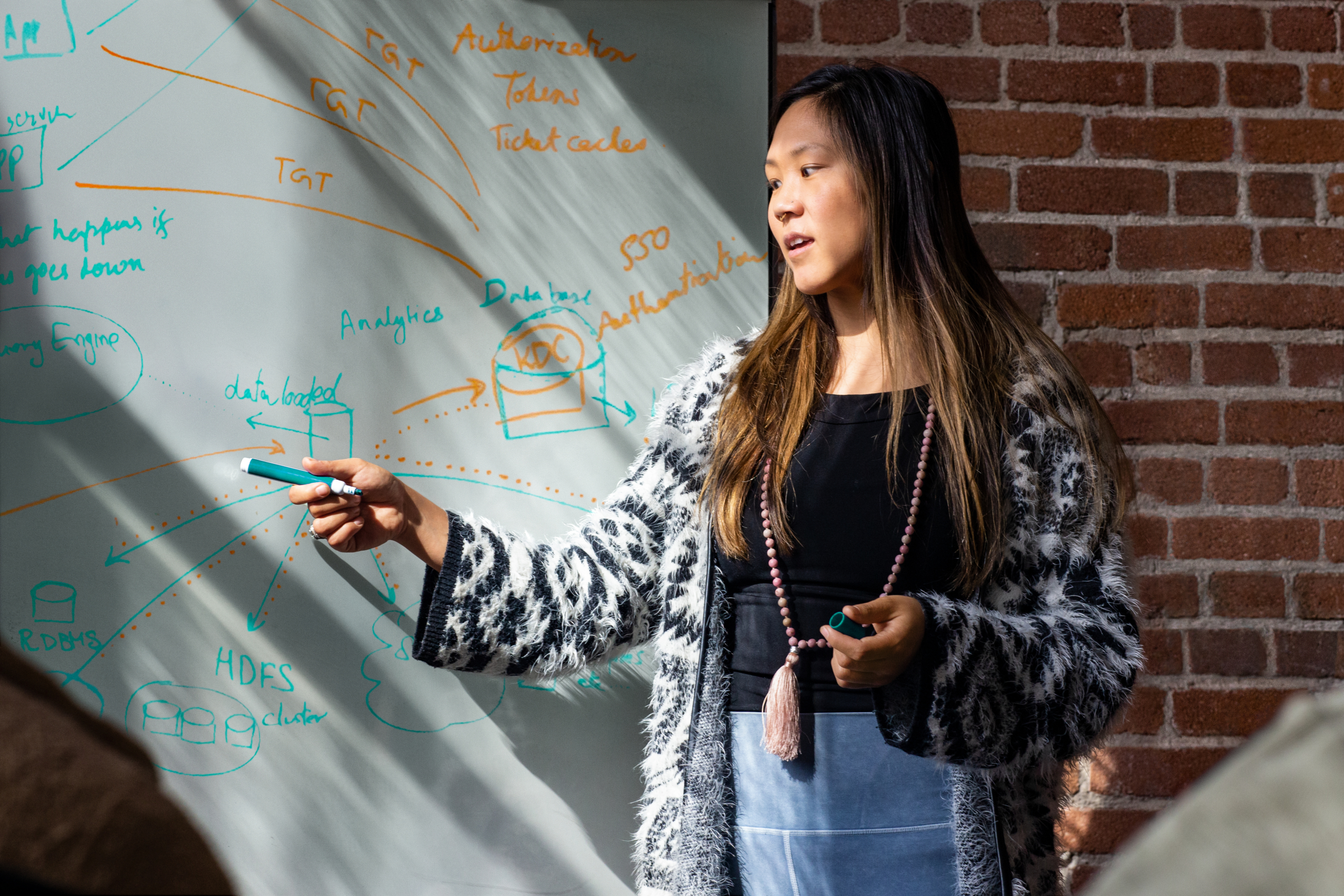 Real people, real offices. Female developer speaking in front of a white board during team stand up meeting. Women who code, women developers, women engineers, code, develop, developer, engineer, Visual Studio, Azure
