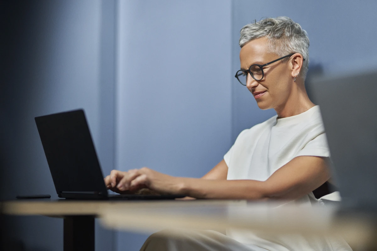 Woman smiling in workspace while on laptop