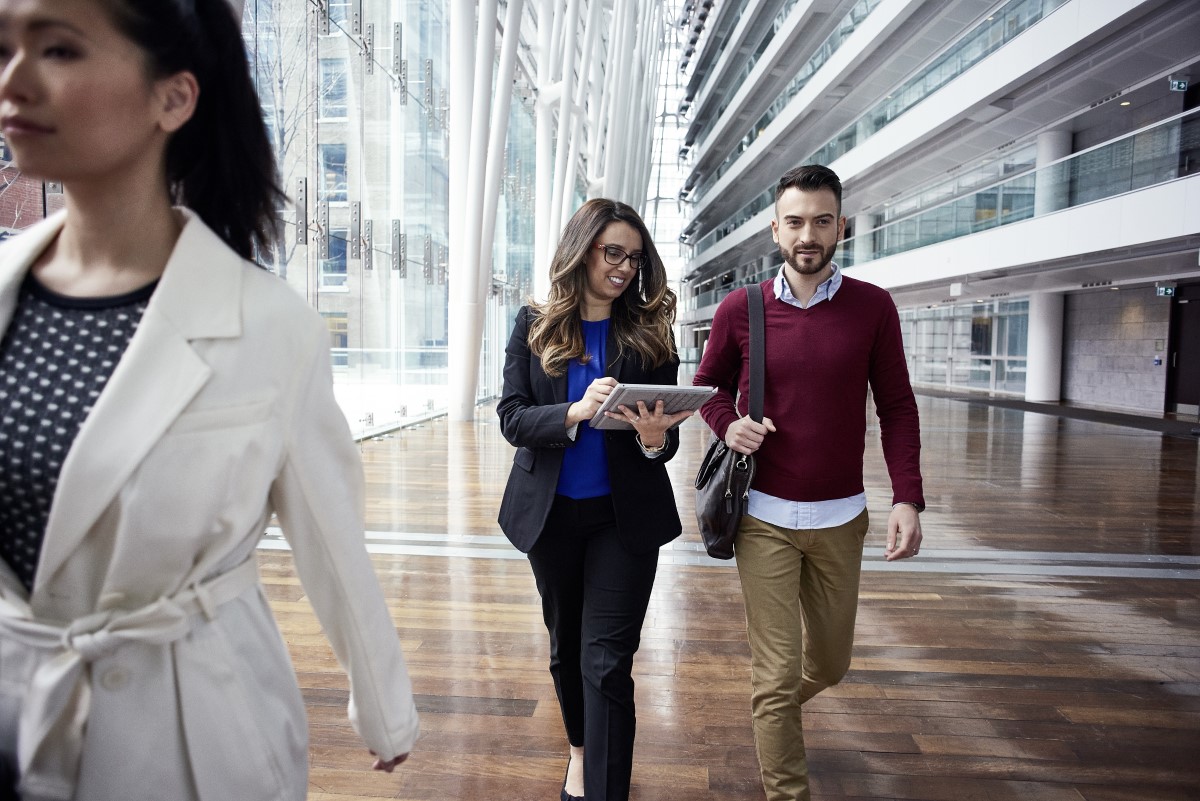 Female and male business professionals walking in foyer working on a Surface Pro