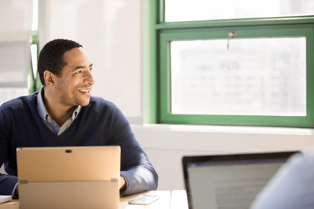 Man sits at a desk with a computer and looks out the window