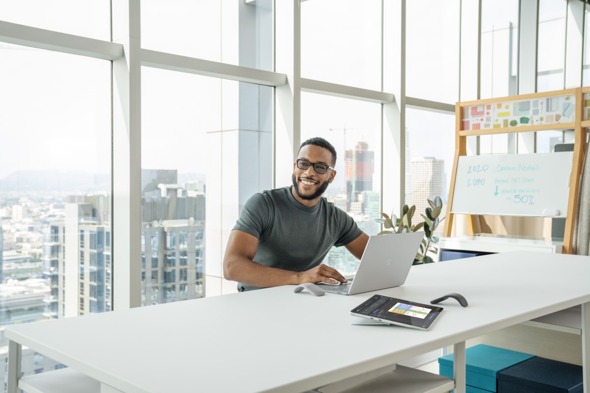 Person sitting at a desk with a laptop, smiling, looking to the side