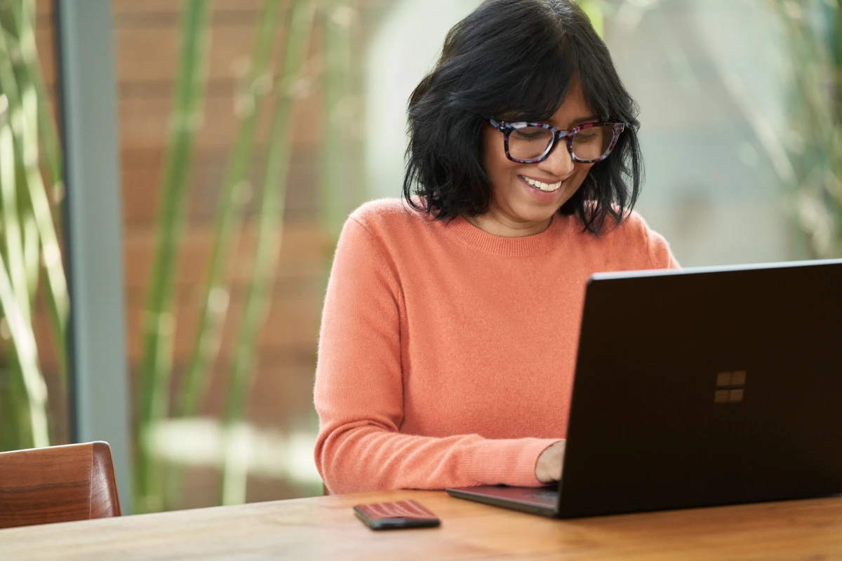 A woman who is sitting at her laptop working and smiling