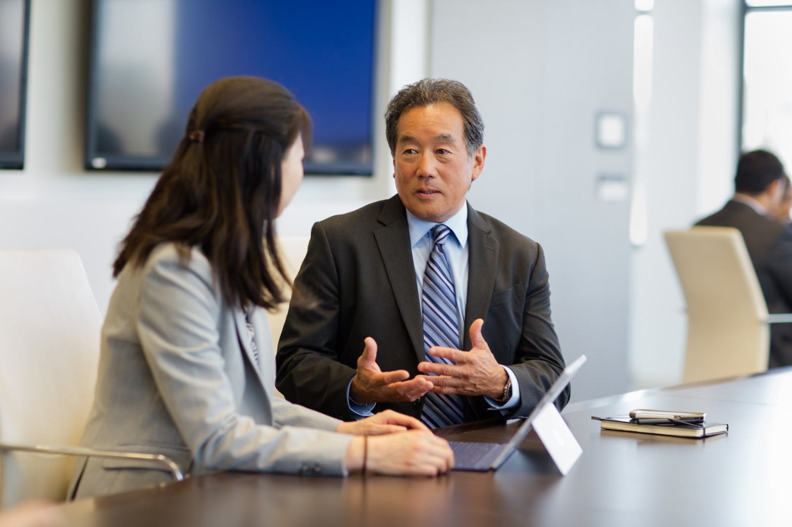 Two executives in a discussion in a conference room. Business attire