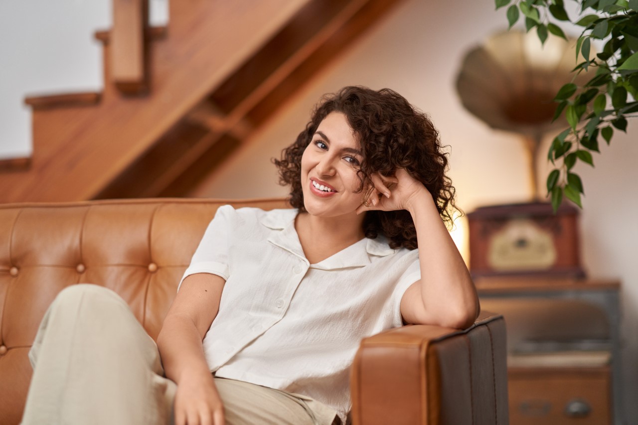 A portrait of a woman sitting on a couch, leaning on the arm rest