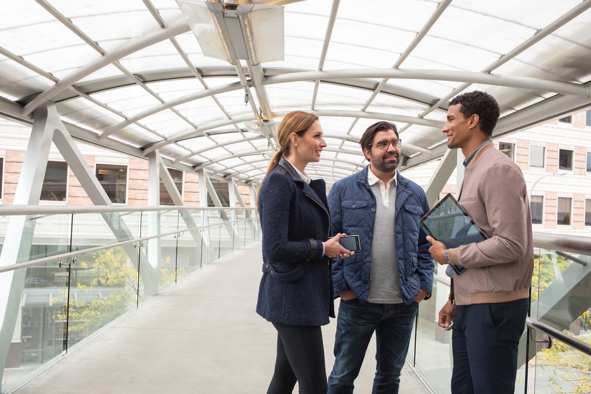 Business people on office skybridge with tablet and phone