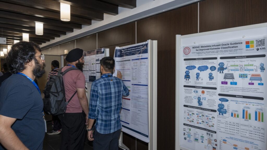 Photograph of a conference hallway with multiple research posters displayed on white stands, showing scientific data, charts, and text. Attendees, including a man in a plaid shirt with a backpack, are viewing the posters, indicating an academic or professional event focused on sharing research findings.