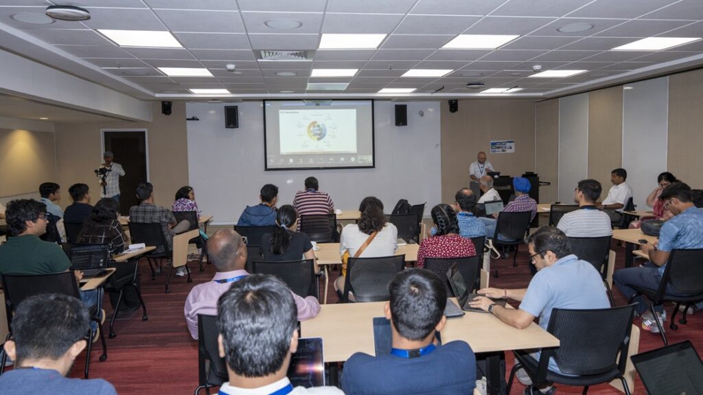 Photograph of an audience of a group of people seated at tables facing a speaker at the podium.