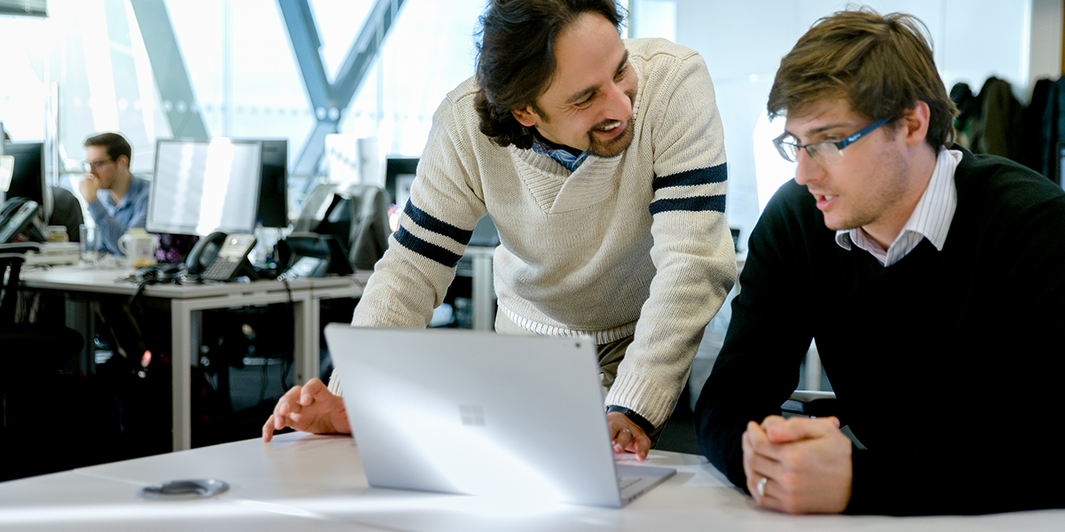 Image of two coworkers collaborating over a laptop