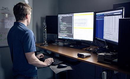 A tech worker uses a dual screen PC workstation