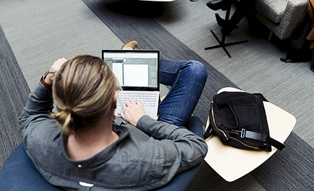 Image of a man with a pony tail seen from above working on his laptop