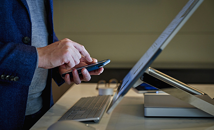 Image of a workers hands holding a device. A finger is about to tap on the screen