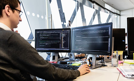 A tech worker using a dual screen PC workstation