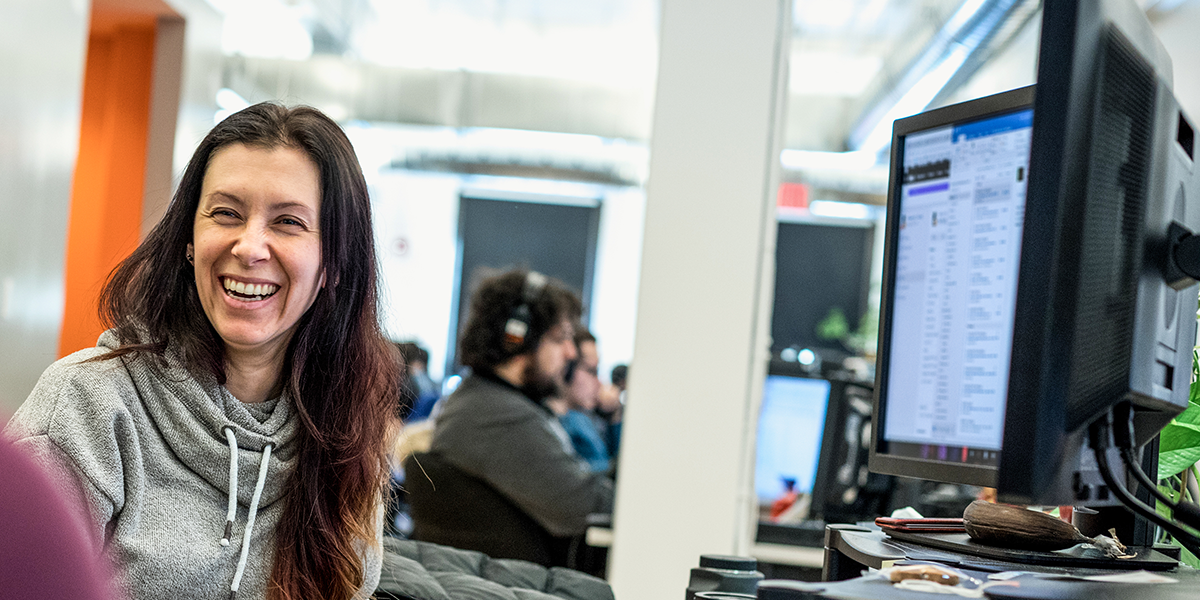 Image of a woman in an IT department smiling at her desk