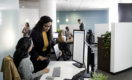 Two women collaborate over a desk at work