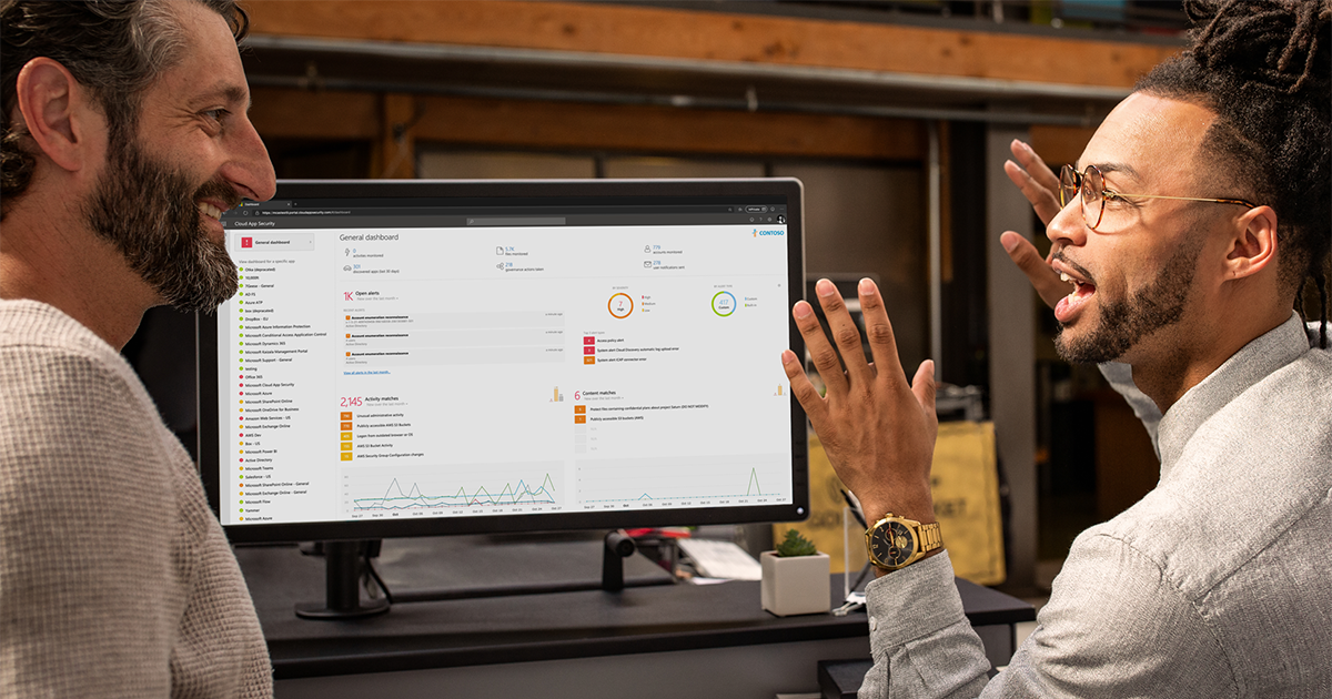 Image of two workers talking next to a computer monitor