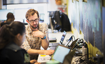 Image of several coworkers collaborating over a computer in an office