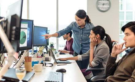 Image of coworkers pointing at a computer monitor
