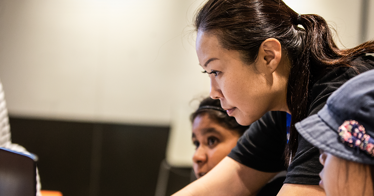 Image of a dev helping students in a classroom