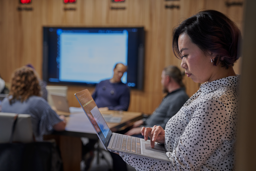 Women looking at Surface laptop with background of a conference room