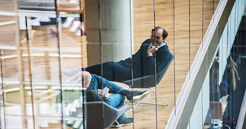 Image of two executives in the tech industry chat while seated in common area of UK office