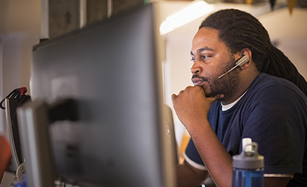 Tech worker in front a PC wearing headphones