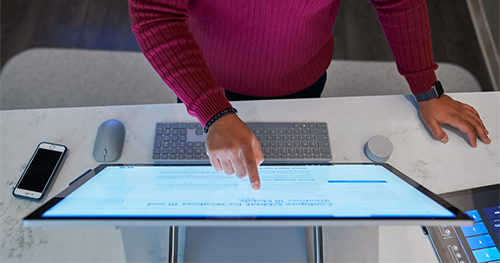 Top down view of a man wearing a dark red shirt working on a Microsoft Surface Studio