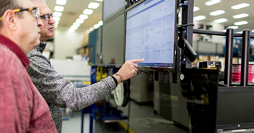 An image of two tech workers looking at a PC display in a data center